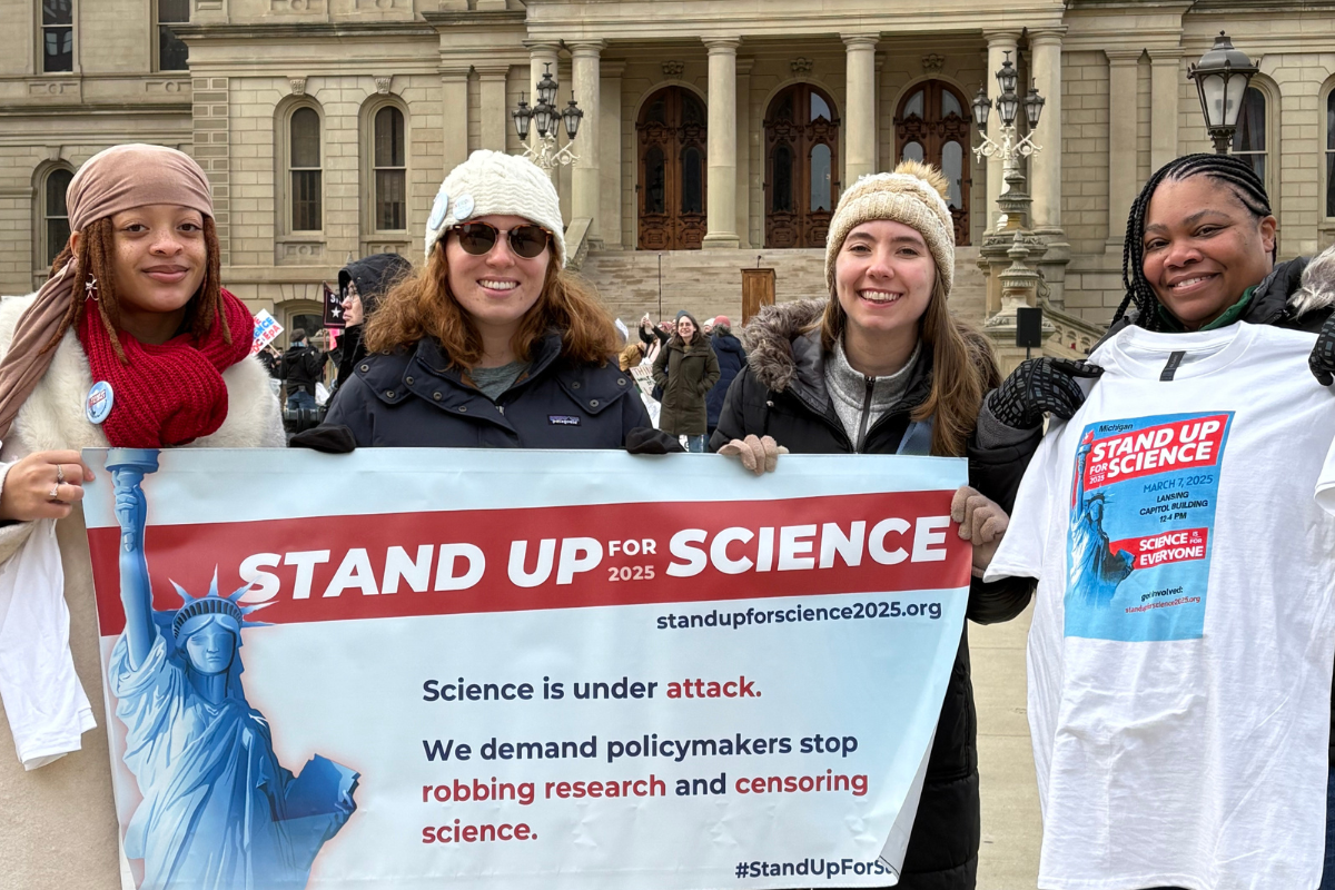 Four Stand Up for Science rally participants holding a banner.